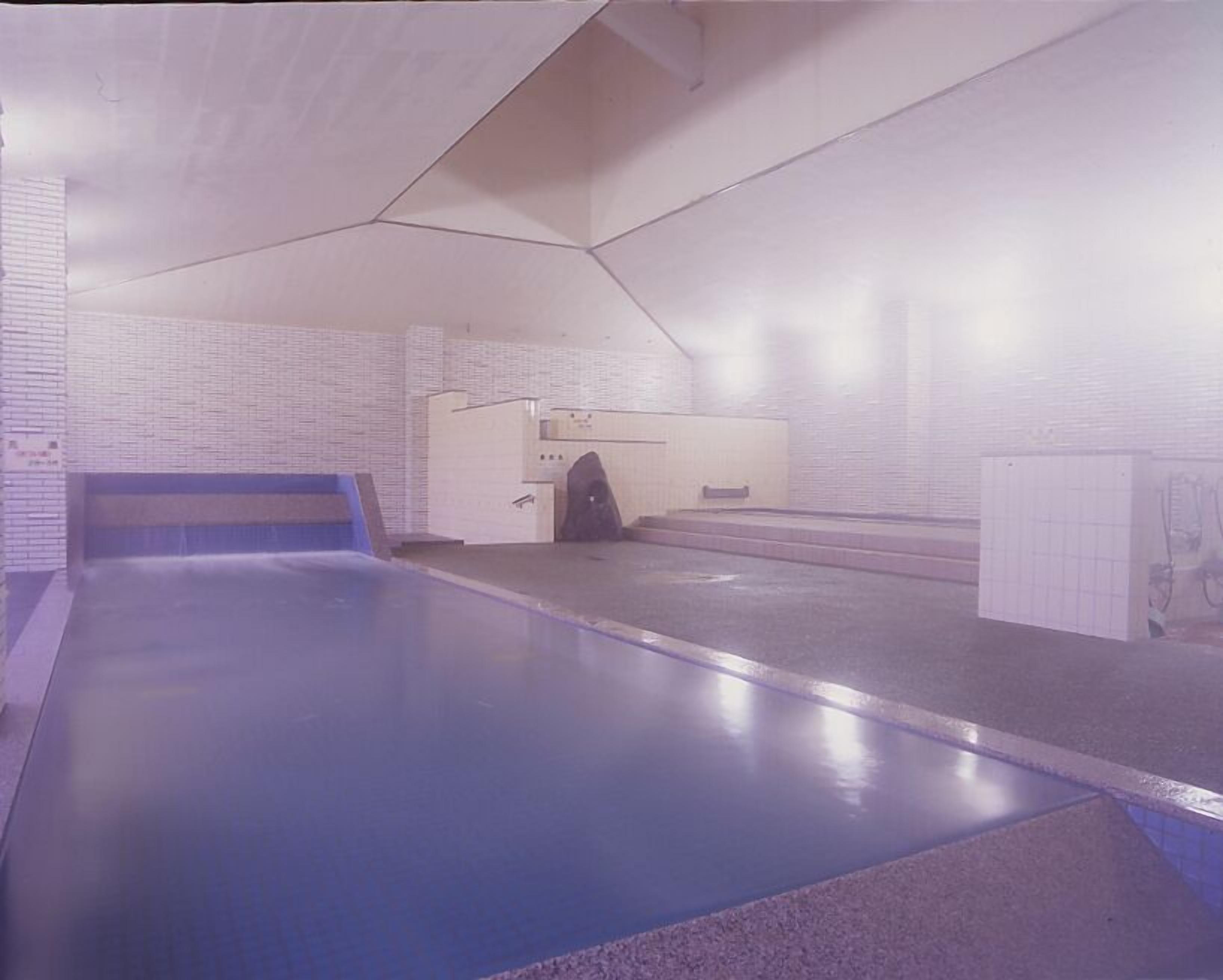 An indoor swimming pool with a blue lane, a changing room, and a reception area.