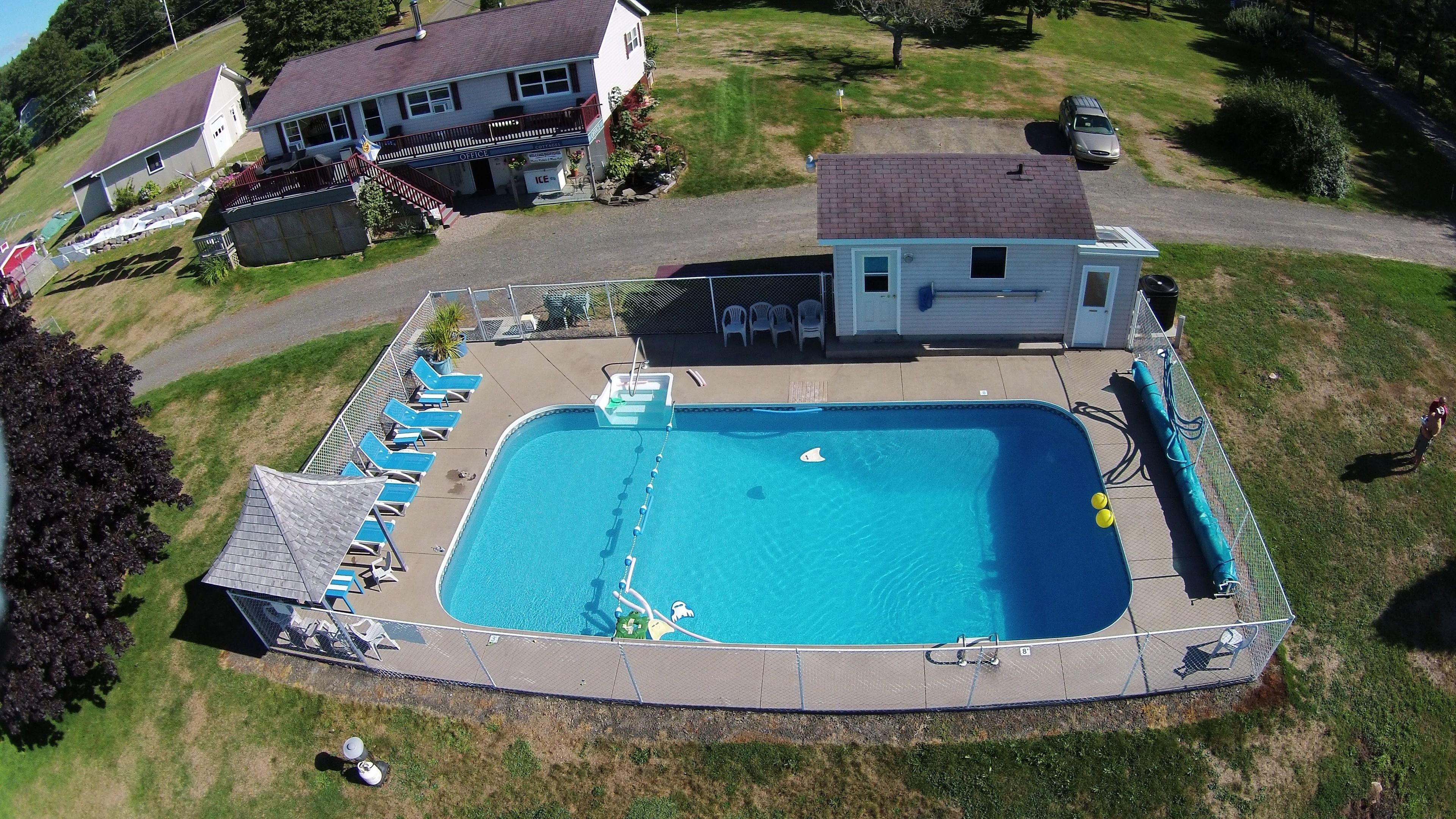 A rectangular swimming pool with a deck, surrounded by a fence, and a small building labeled "OFFICE" in the background.