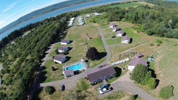 Vista aérea de um camping com veículos recreativos, casas e uma piscina.