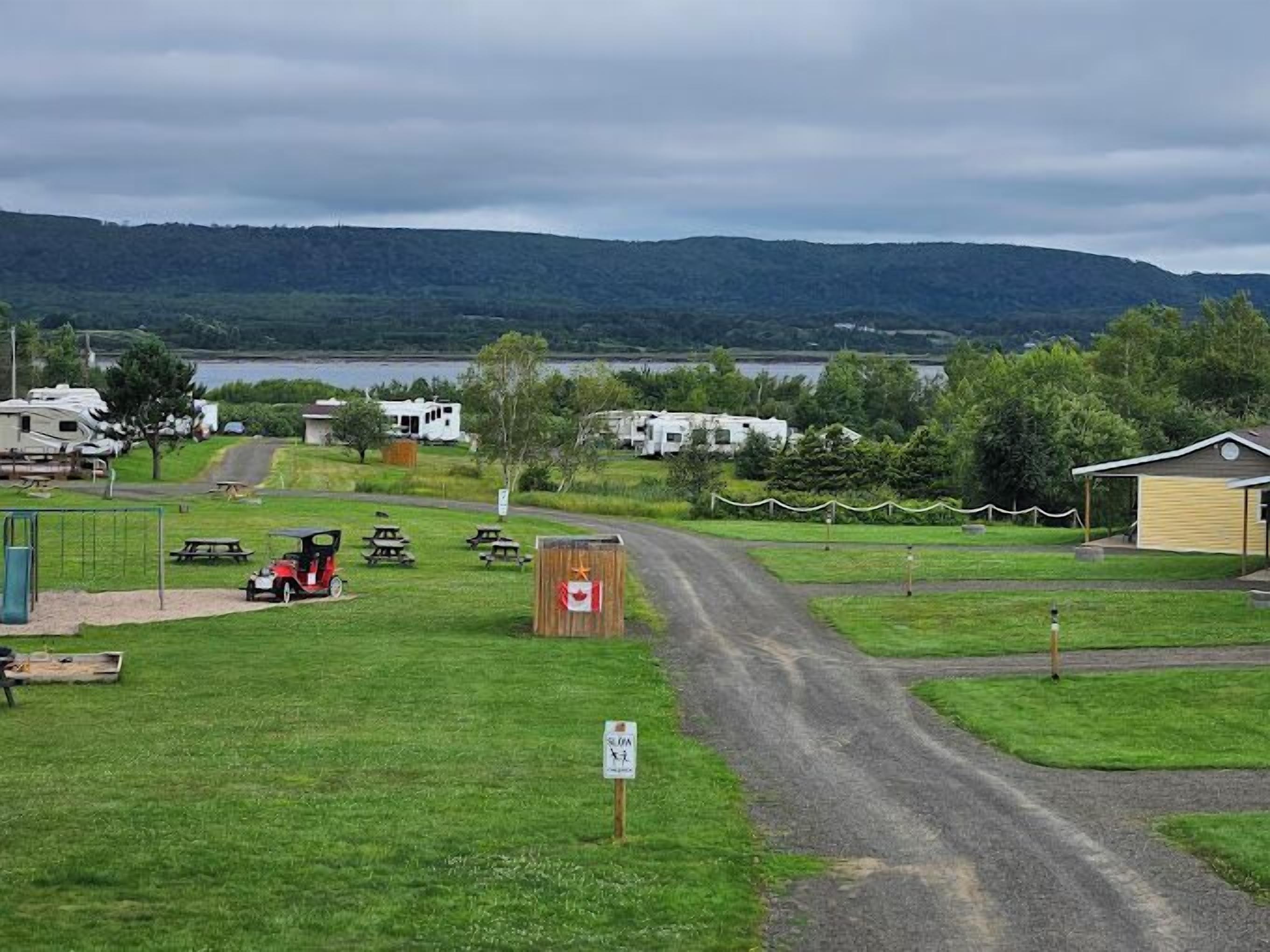 A campground with RVs, picnic tables, and a small building.