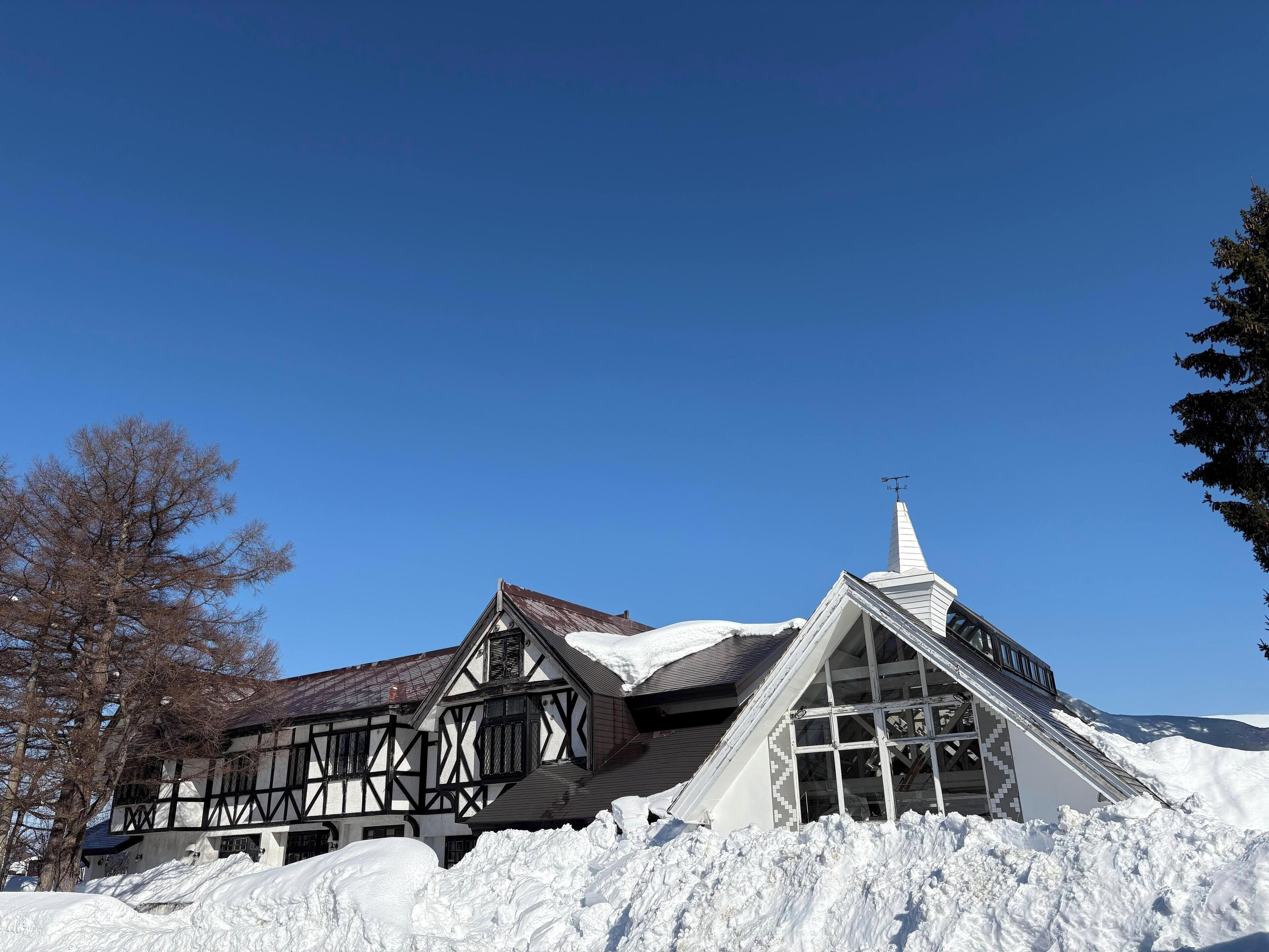 Een traditioneel vakwerkhuis met een steil dak en een opvallende schoorsteen, omgeven door sneeuw.
