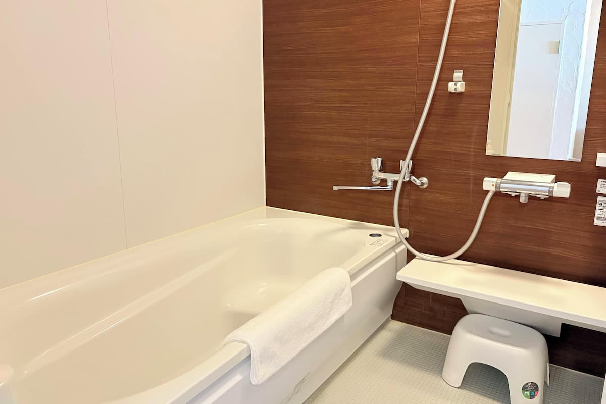 deluxe room | bathroom | combined shower/bathtub, hair dryer, slippers, bidet
