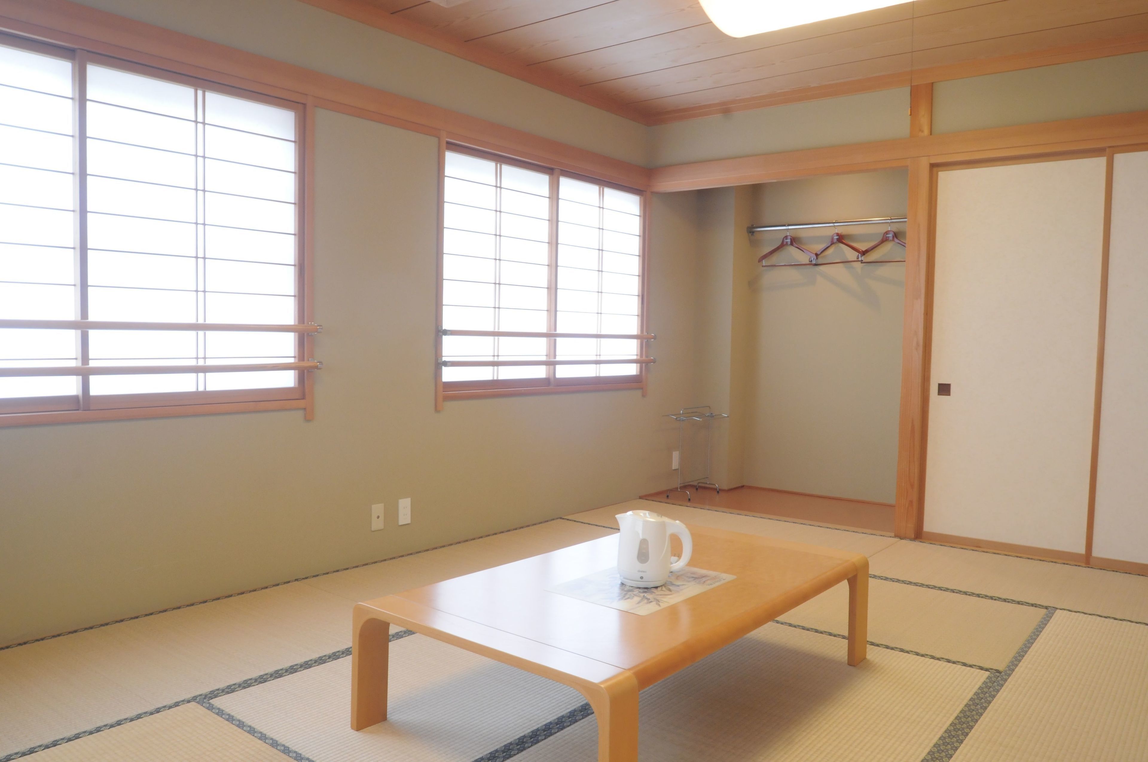 A traditional Japanese room with tatami flooring, a wooden table, a shoji screen, and a sliding door.