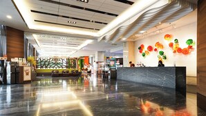 A modern hotel lobby with a polished marble floor, a reception desk, and a wall decorated with colorful floral art. - HOYA Resort Hotel Kaohsiung (Kaohsiung)