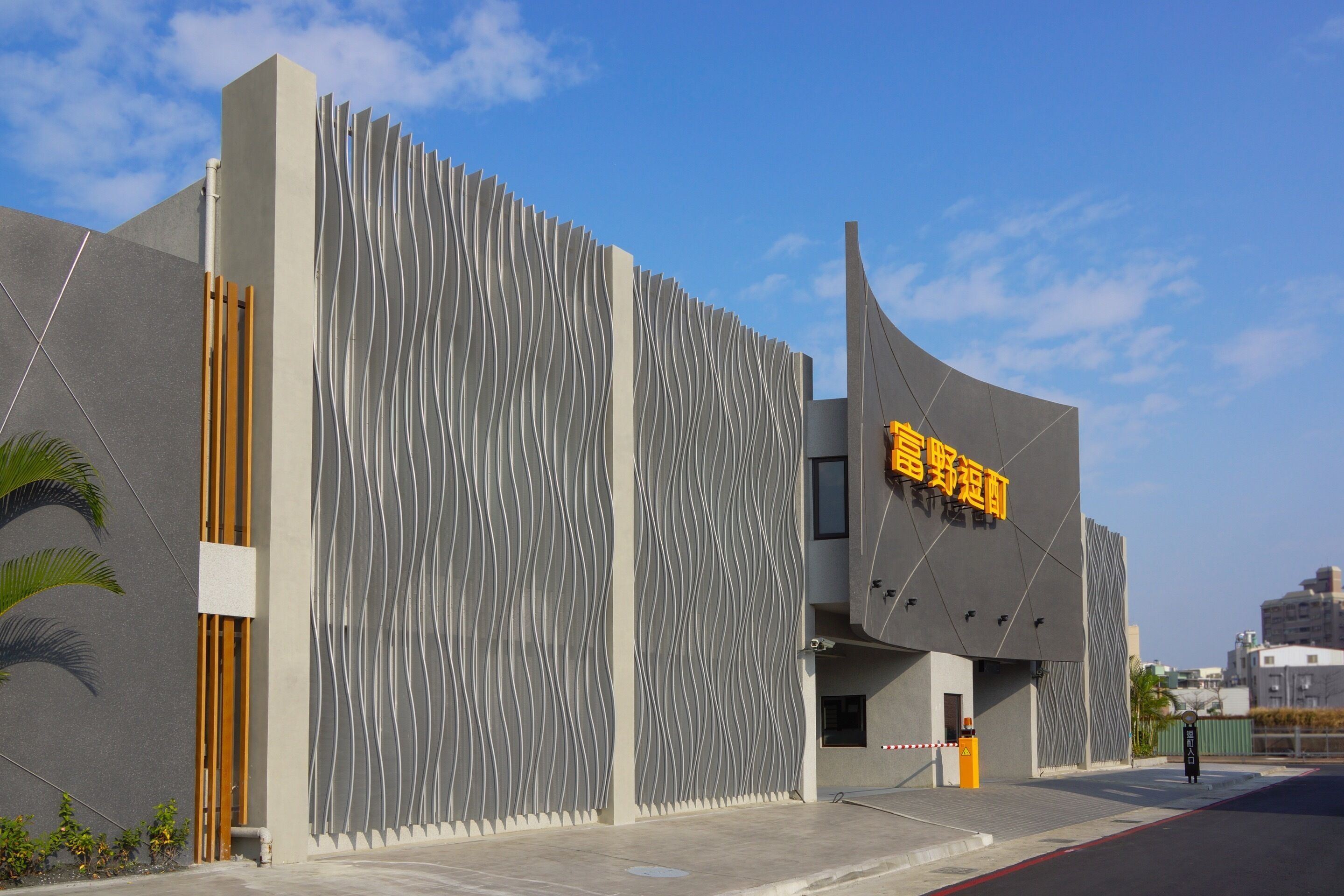 A modern building with a unique wavy facade and a prominent yellow sign.