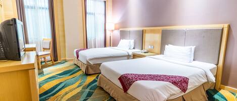 A hotel room with two beds, a desk with a computer, and a chair.