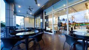 An indoor dining area with round tables and chairs, ceiling fans, and large windows. - Imperial Palace Hotel (Miri)