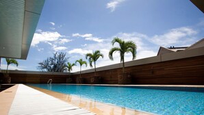 A swimming pool with a wooden deck and palm trees in the background. - Imperial Palace Hotel (Miri)