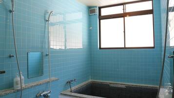 A bathroom with blue tiled walls, a window, a bathtub, and a shower.