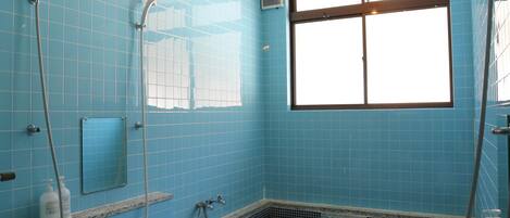 A bathroom with blue tiled walls, a window, a bathtub, and a shower.