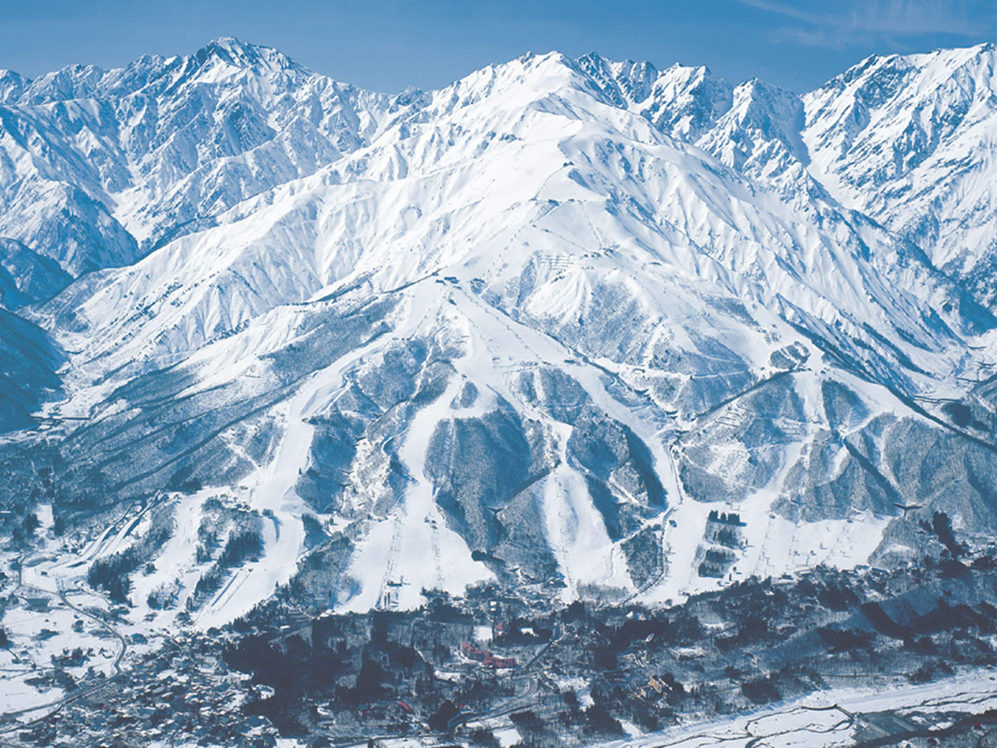 Ein schneebedecktes Gebirge mit einer Stadt am Fuße.