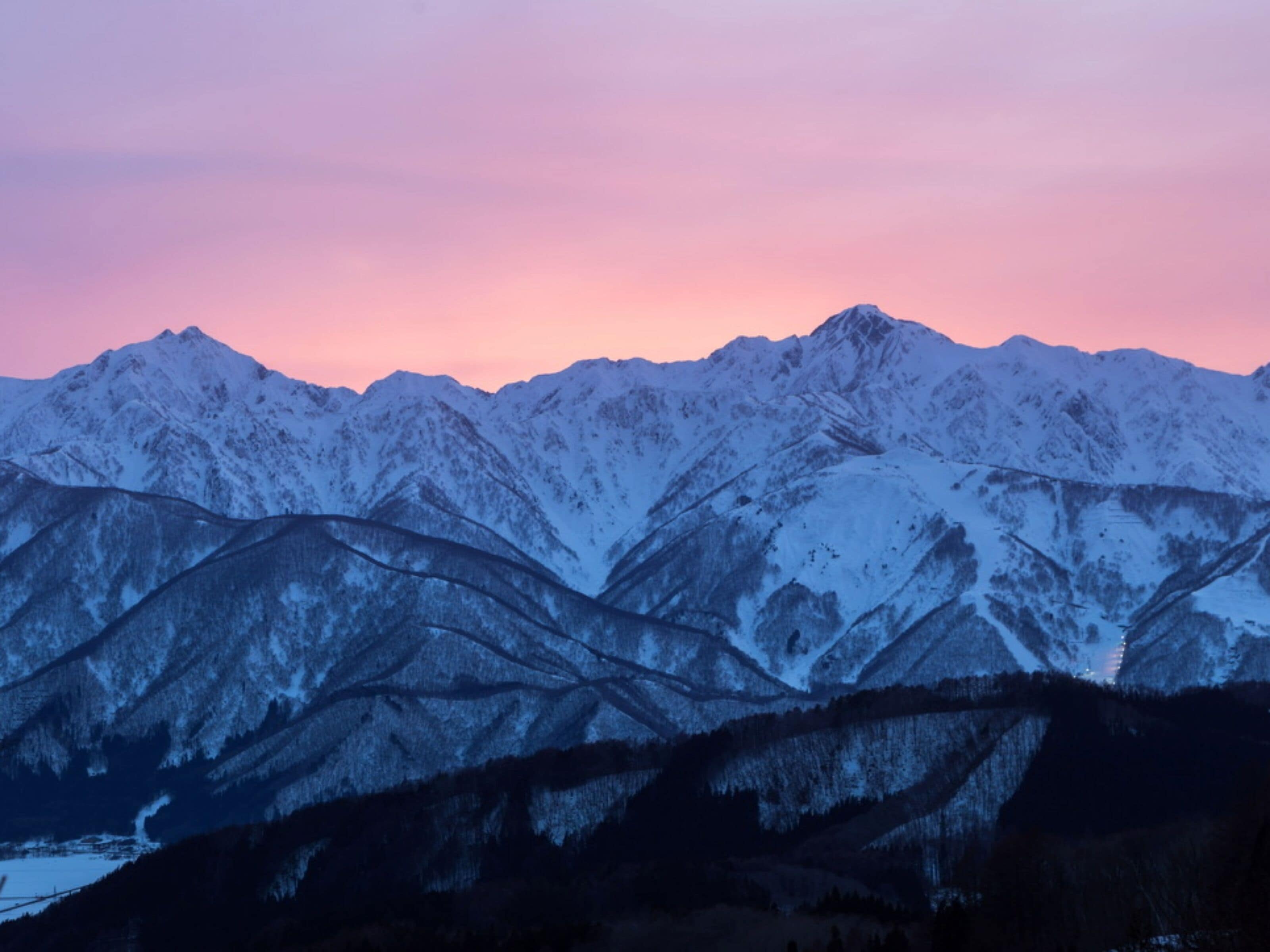 A mountain range with snow-covered peaks and a clear sky.