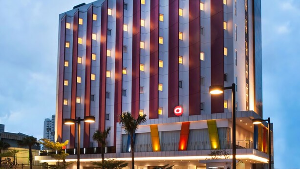 Un hotel de varios pisos con diseño moderno, que presenta un logotipo destacado en la fachada y una serie de ventanas regularmente espaciadas.