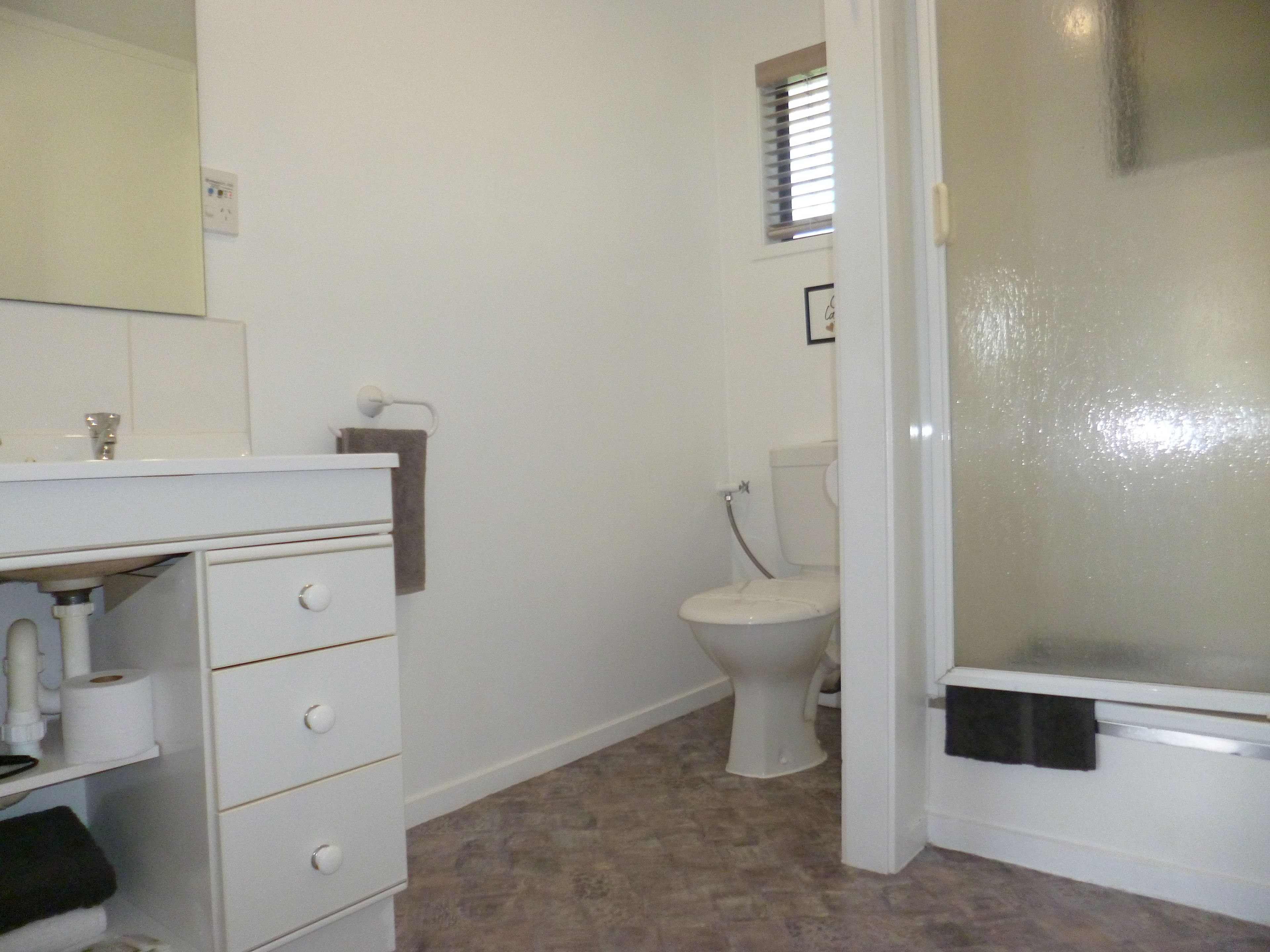 A bathroom with a toilet, sink, and shower area.