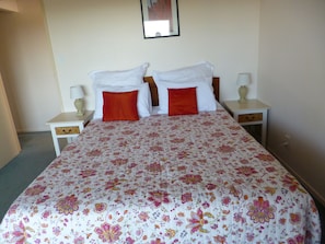 A double bed with floral bedding, two nightstands with lamps, and a framed picture on the wall.