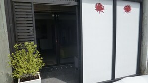 A modern building entrance with a glass door, a potted plant, and a red logo on the wall. - Opua Boutique Seaview Motel (Opua)