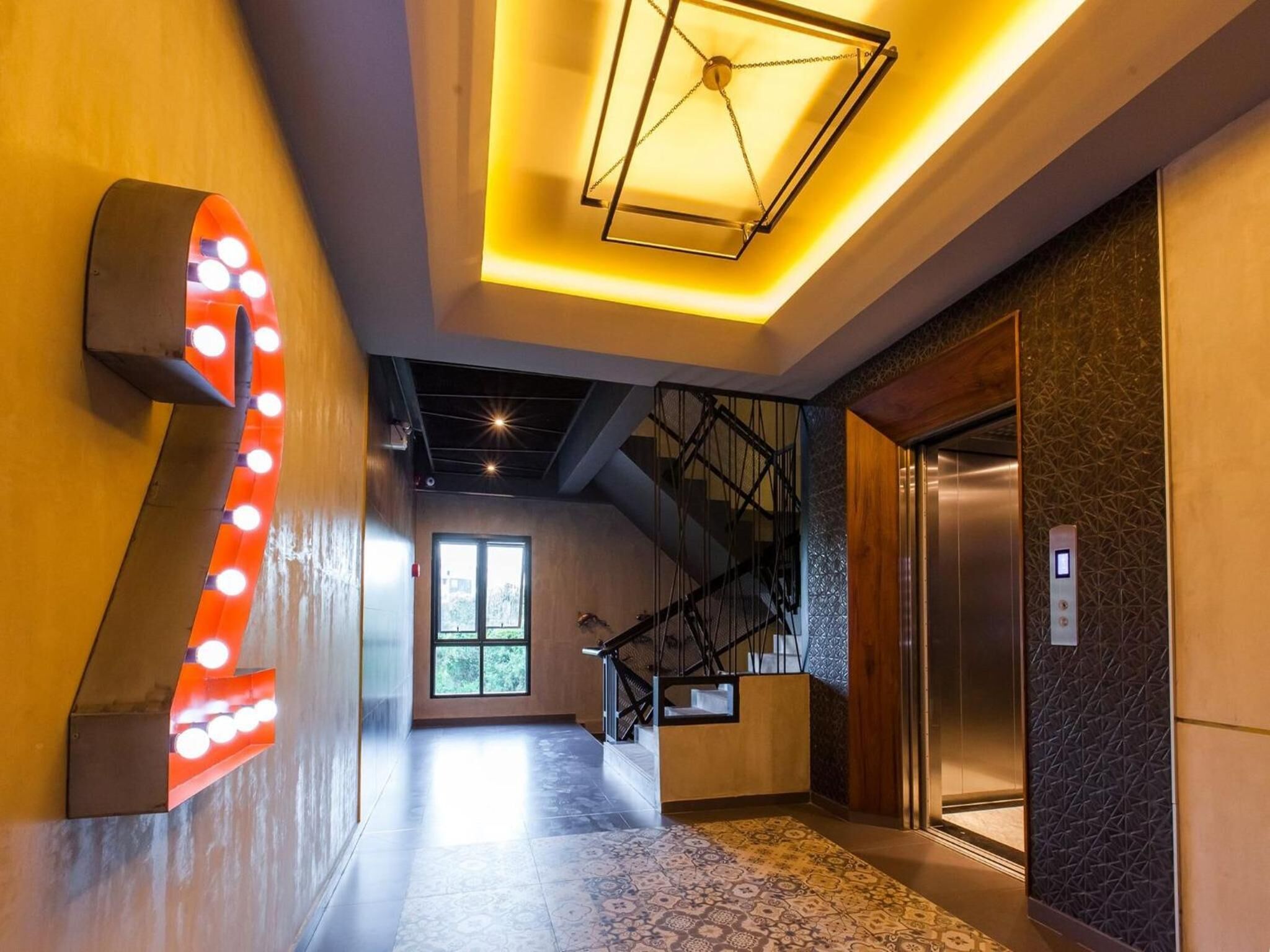 A modern hallway with a large illuminated number '2' sign, a staircase, and an elevator.
