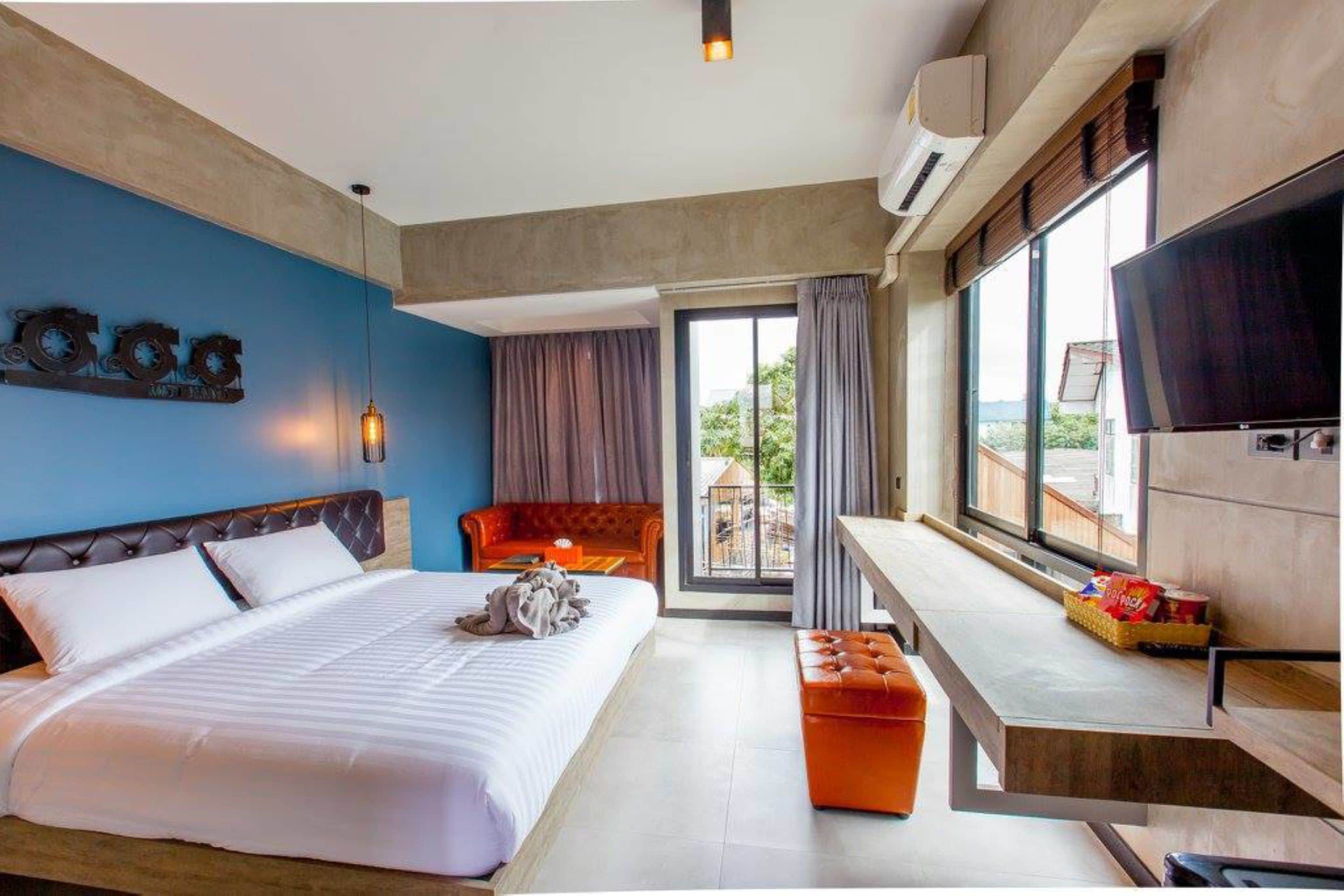 A hotel room with a bed, a sofa, a TV, and a balcony with a view.