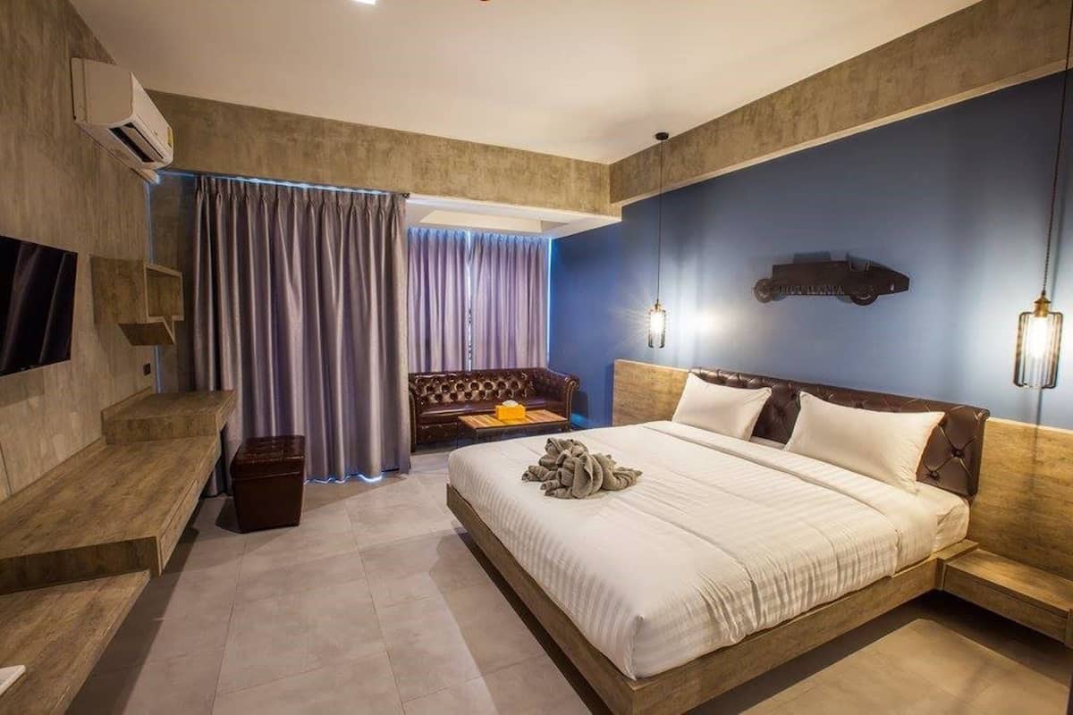 A modern bedroom with a large bed, a sofa, and a TV mounted on the wall.