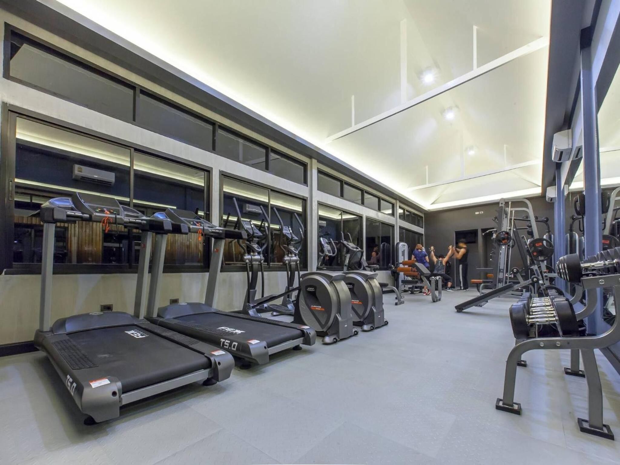 A modern gym with treadmills, elliptical machines, and weightlifting equipment.