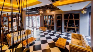 A modern interior with a checkered floor, wooden furniture, and large windows. - Loftmania Boutique Hotel (Chumphon)