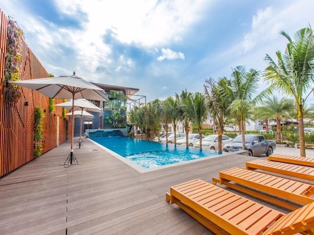 Una piscina al aire libre, sombrillas, sillones reclinables de piscina