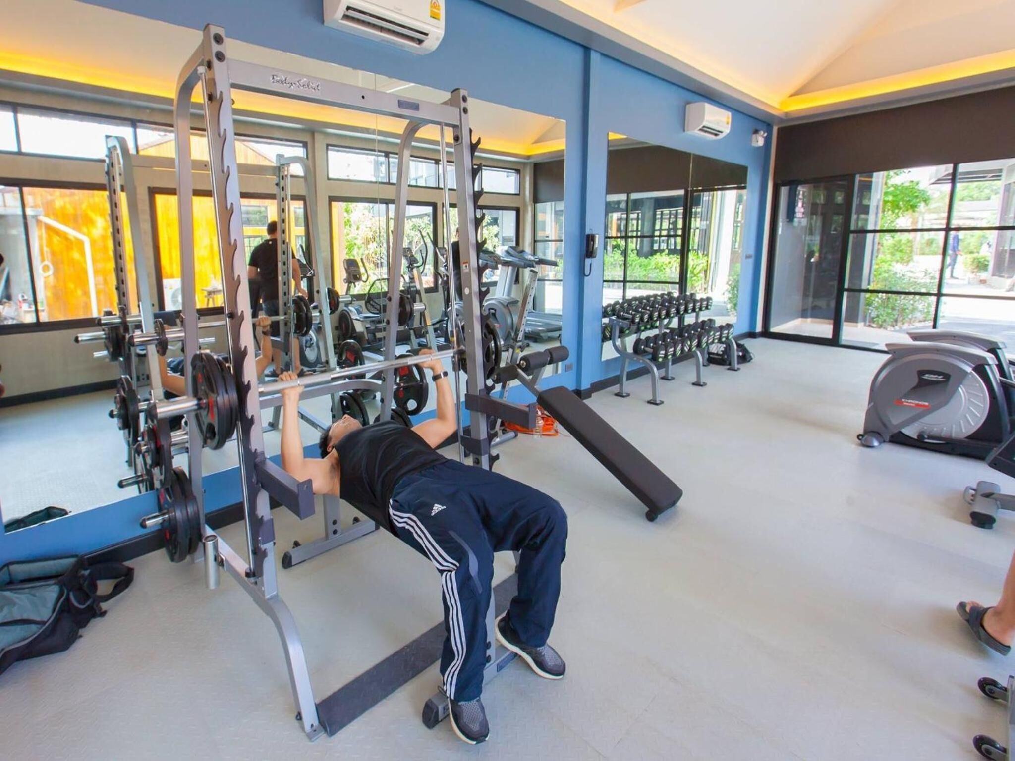 A gym with a variety of exercise equipment, including a squat rack and a bench.