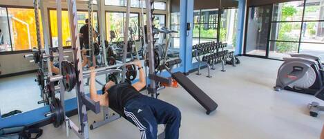 A gym with a variety of exercise equipment, including a squat rack and a bench.