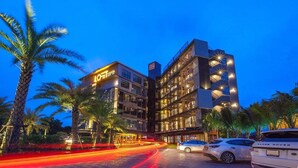 A hotel with multiple floors, a prominent sign, and a parking area with cars. - Loftmania Boutique Hotel (Chumphon)