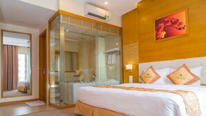 A hotel room with a large bed, a glass-enclosed shower, a wooden headboard, and a painting on the wall. - Palm Hotel Thanh Hoa (Hac Thanh)