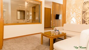 A modern room with a glass partition, a wooden-framed mirror, a sofa, a coffee table, and a decorative panel. - Palm Hotel Thanh Hoa (Hac Thanh)