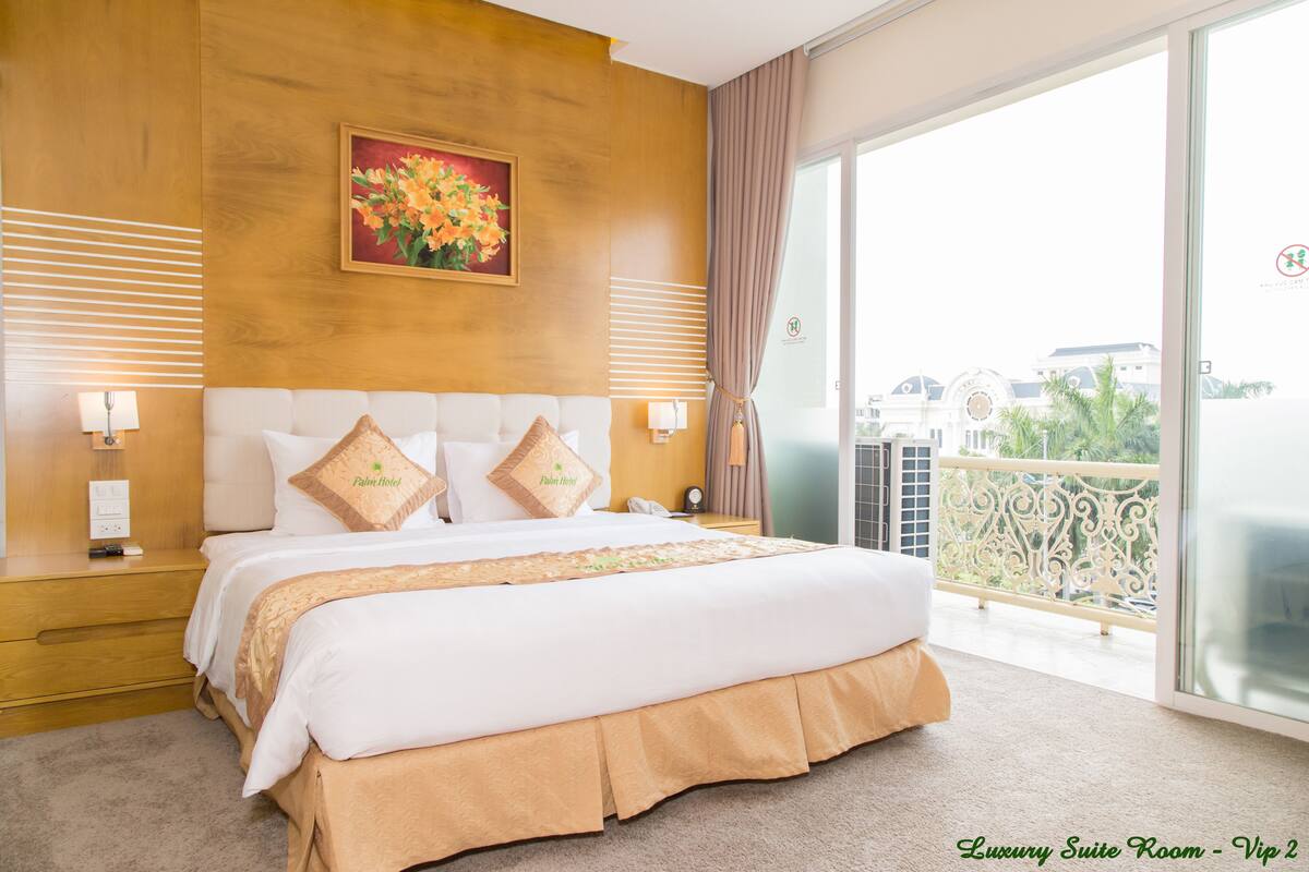Een luxe suitekamer met een groot bed, een schilderij erboven en een balkon met uitzicht.