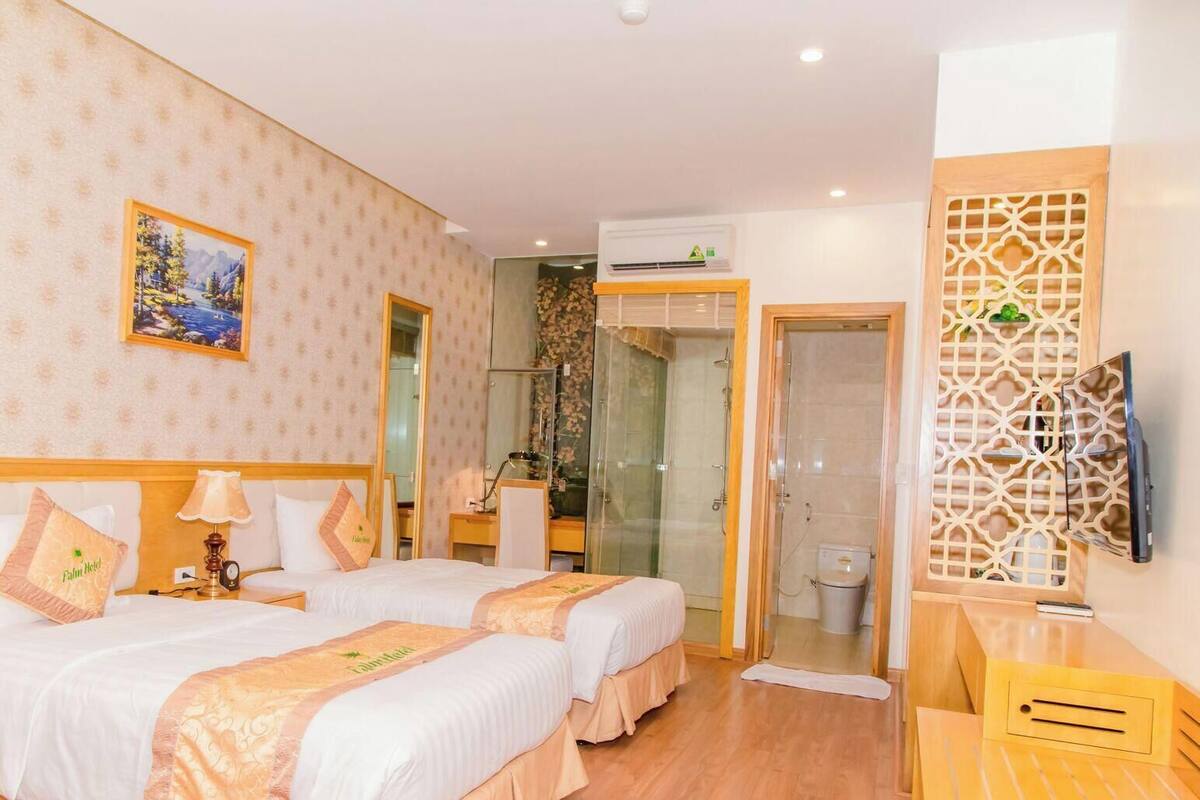 Een hotelkamer met twee bedden, een douche, een televisie en een decoratieve wand.