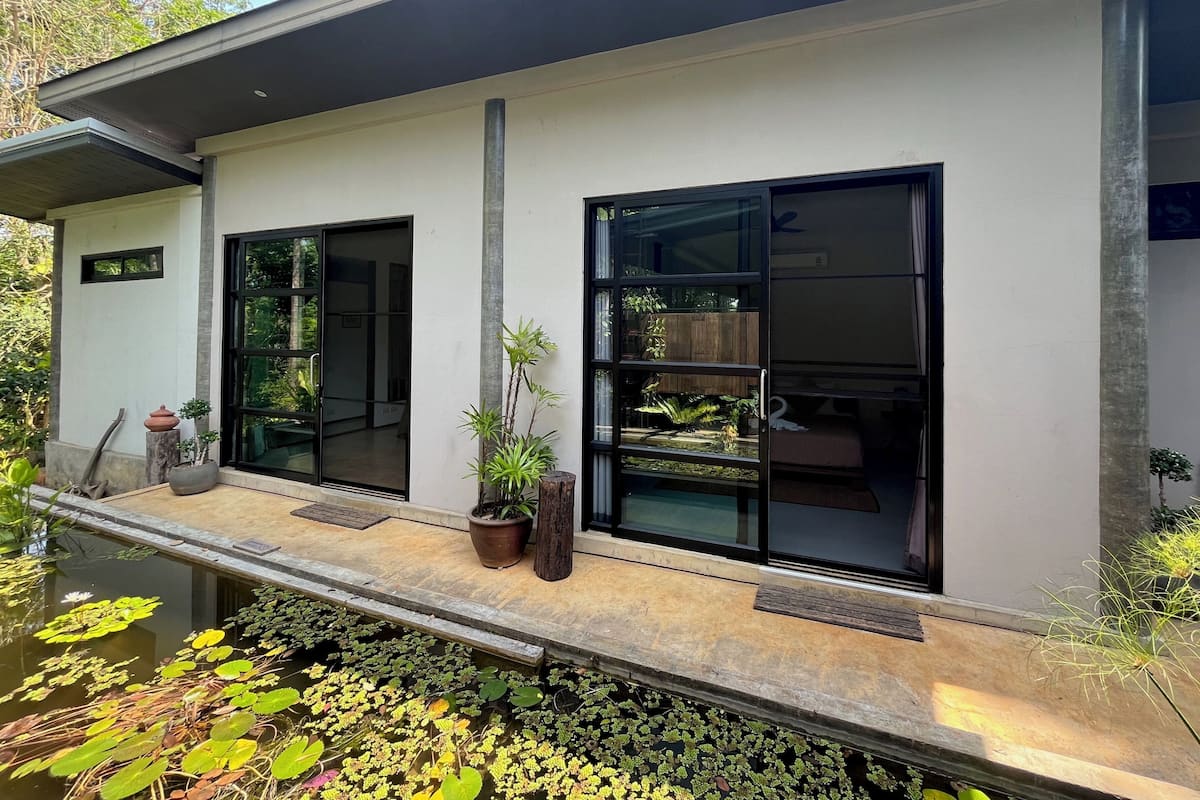 A modern building with large windows, a balcony, and a pond with water lilies.
