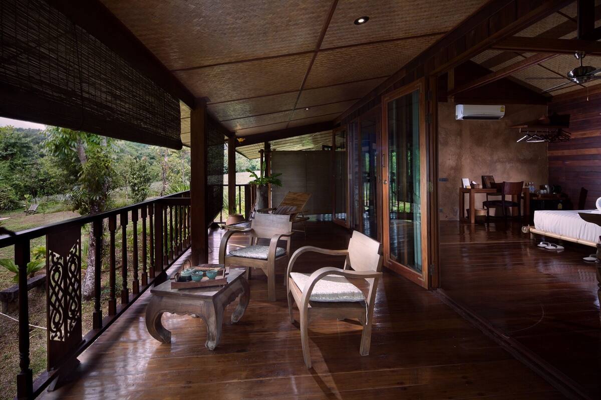 A wooden deck with a dining area, including a table and chairs, and a view of the outdoors.