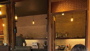 Ein Restaurant mit Steinwand, Holztischen und einer Rezeption.