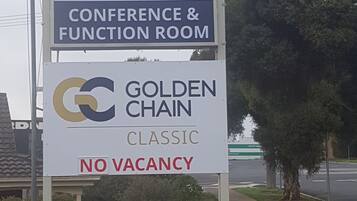 Placa do Colonial Lodge Motel anunciando uma sala para conferências e eventos, e Golden Chain Classic, sem quartos disponíveis.