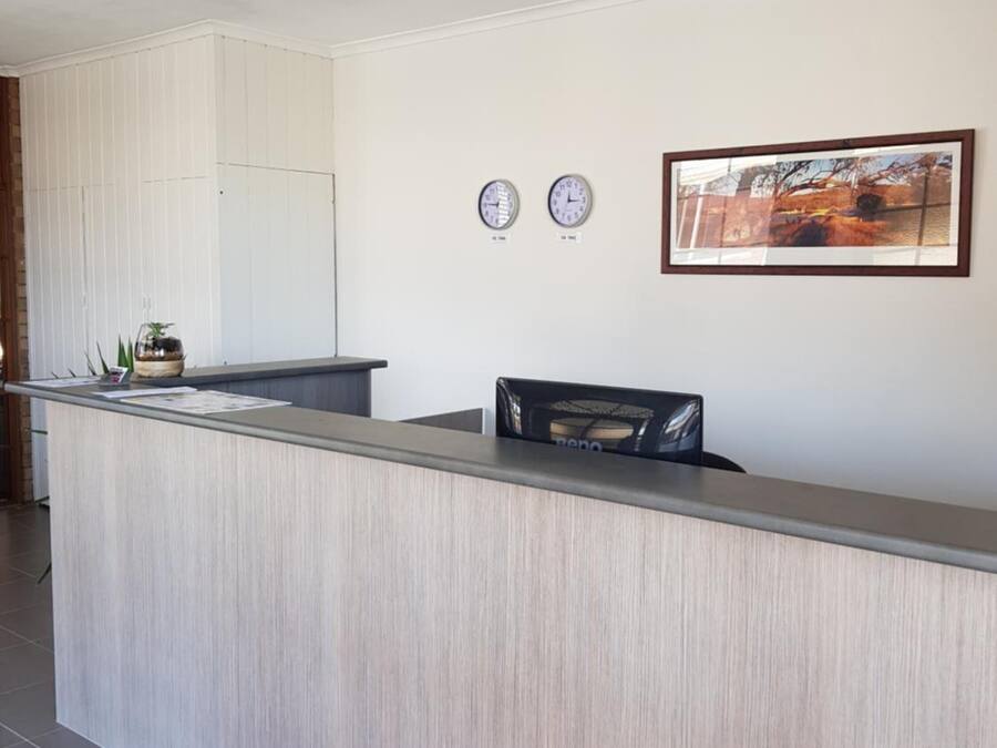 A reception desk with a red carpet, two wall clocks, and a framed picture.