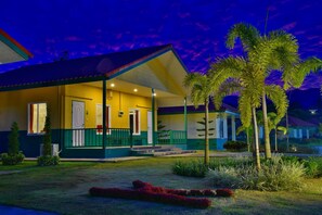 A two-story building with a yellow facade and green trim, featuring a covered porch and a small garden with palm trees. - Kaeo Fa Sai Resort (Chiang Rai)