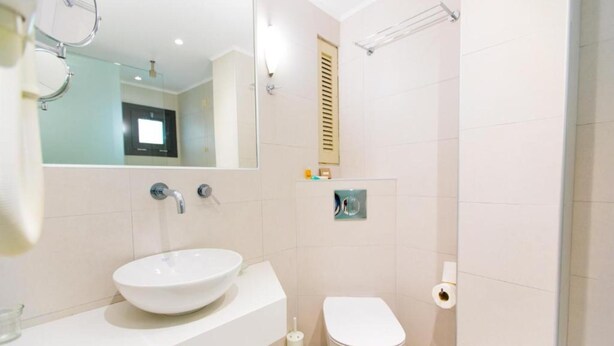 Une salle de bain moderne avec un lavabo blanc, des toilettes et un espace douche.