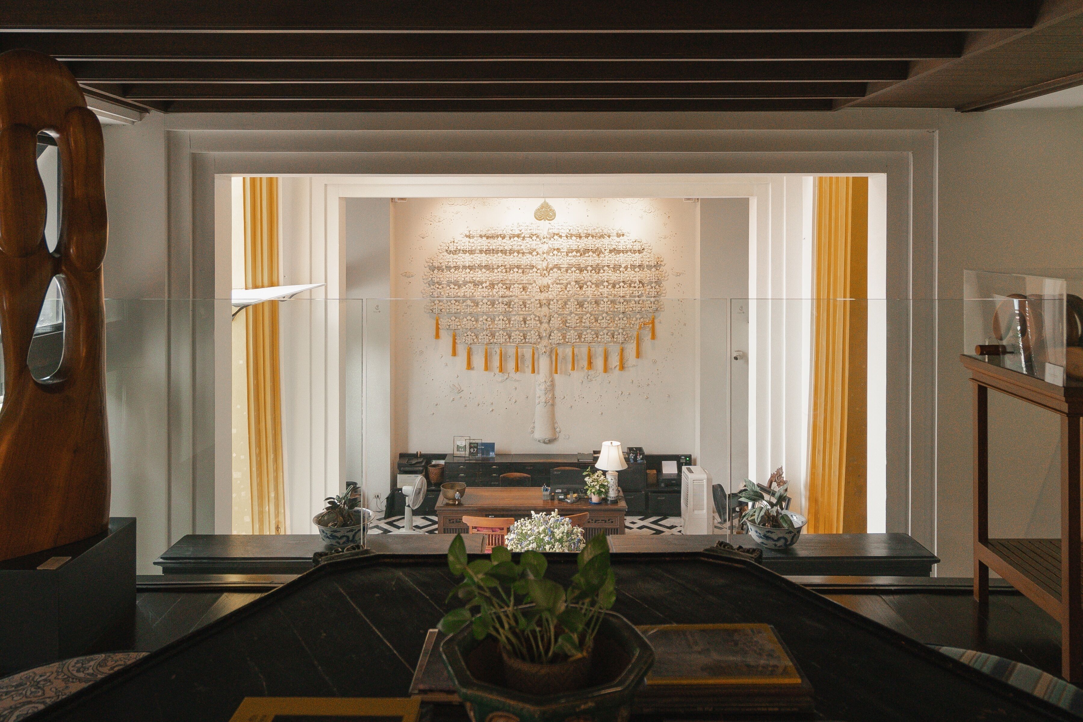 A modern room with a long table, a decorative wall hanging, and a potted plant.