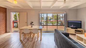 Una sala de estar moderna con comedor, ventanas amplias y televisor.