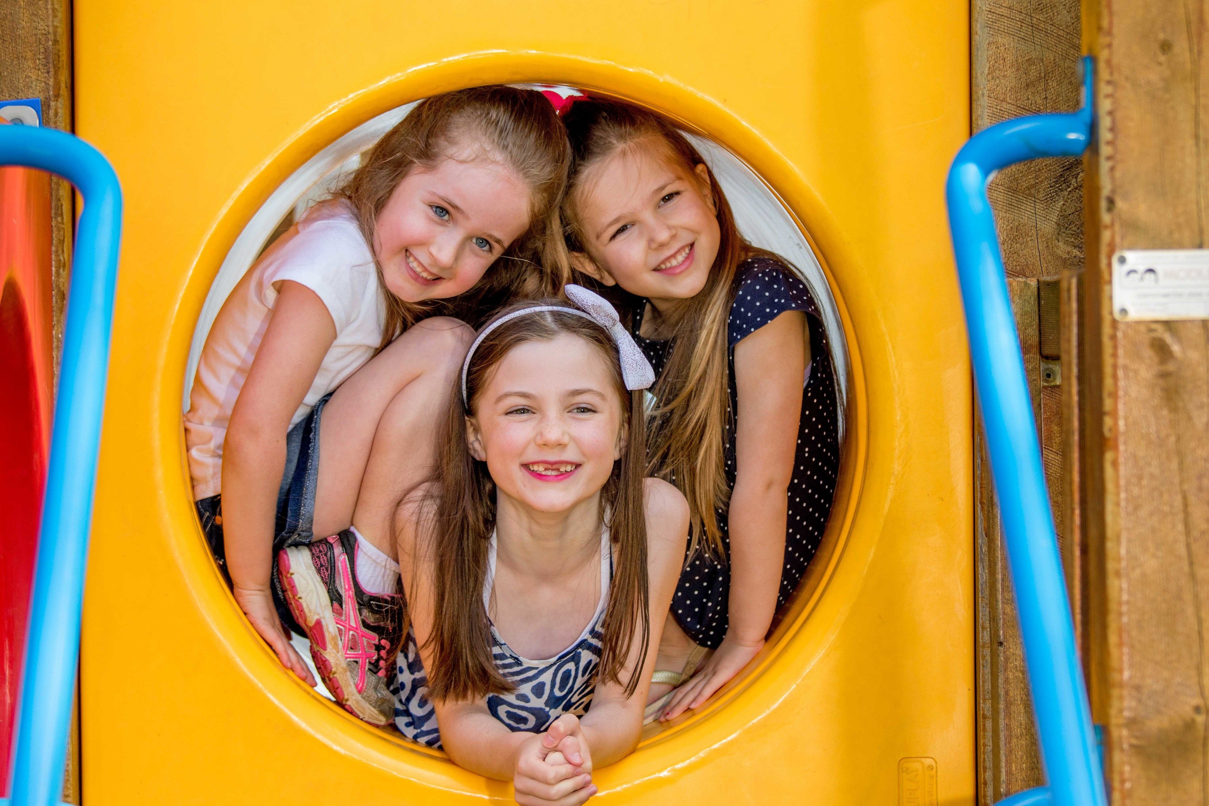 A yellow slide with a circular opening and blue handles.