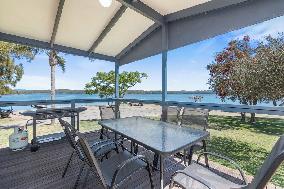 Eine Terrassensitzgelegenheit im Freien mit Tisch und Stühlen, mit Blick auf einen See.