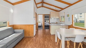 A compact RV interior with a kitchenette, a dining area, and a sleeping space. - Ingenia Holidays Bermagui (Wallaga Lake)