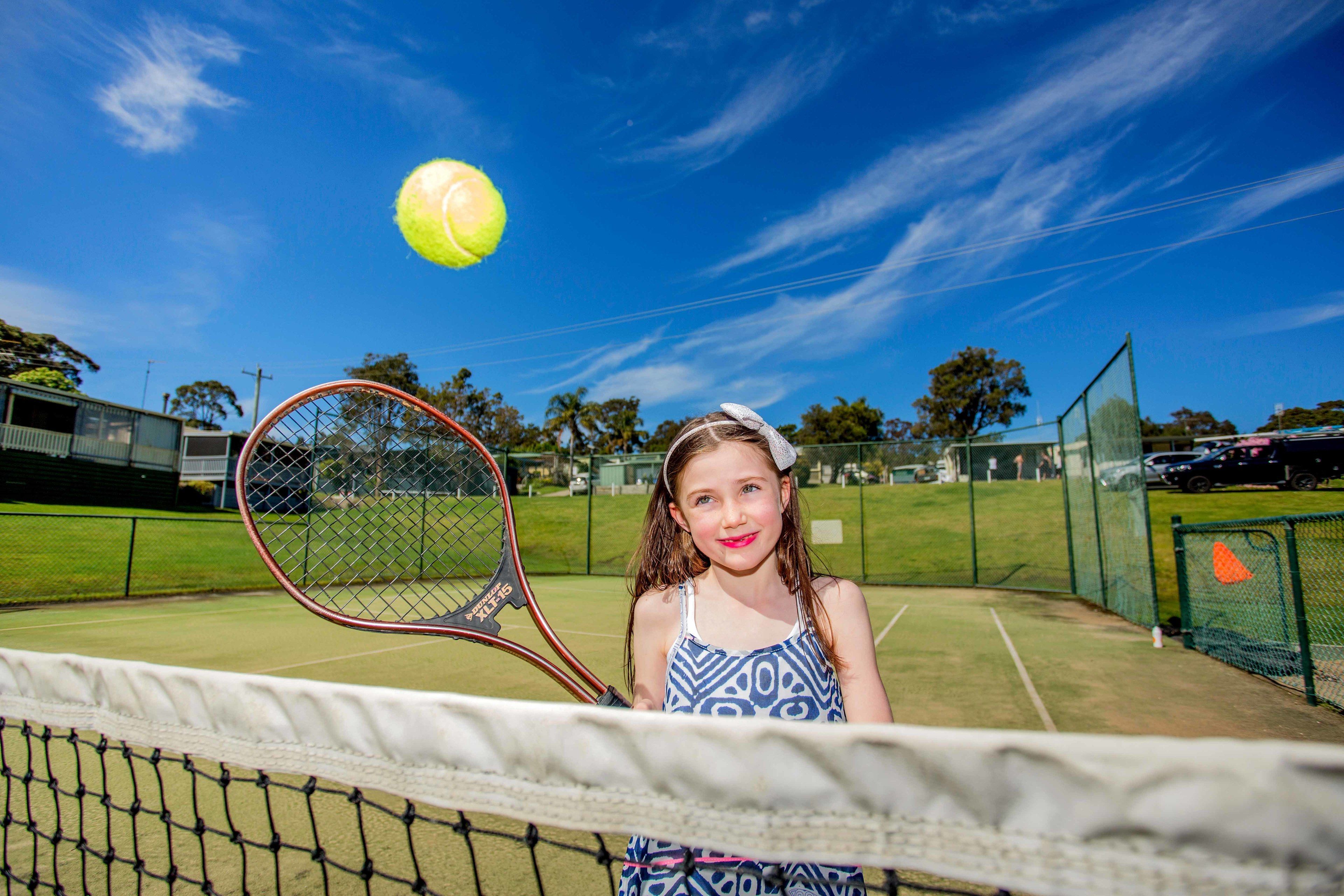 Un court de tennis avec un filet, une raquette de tennis et une balle de tennis en mouvement.