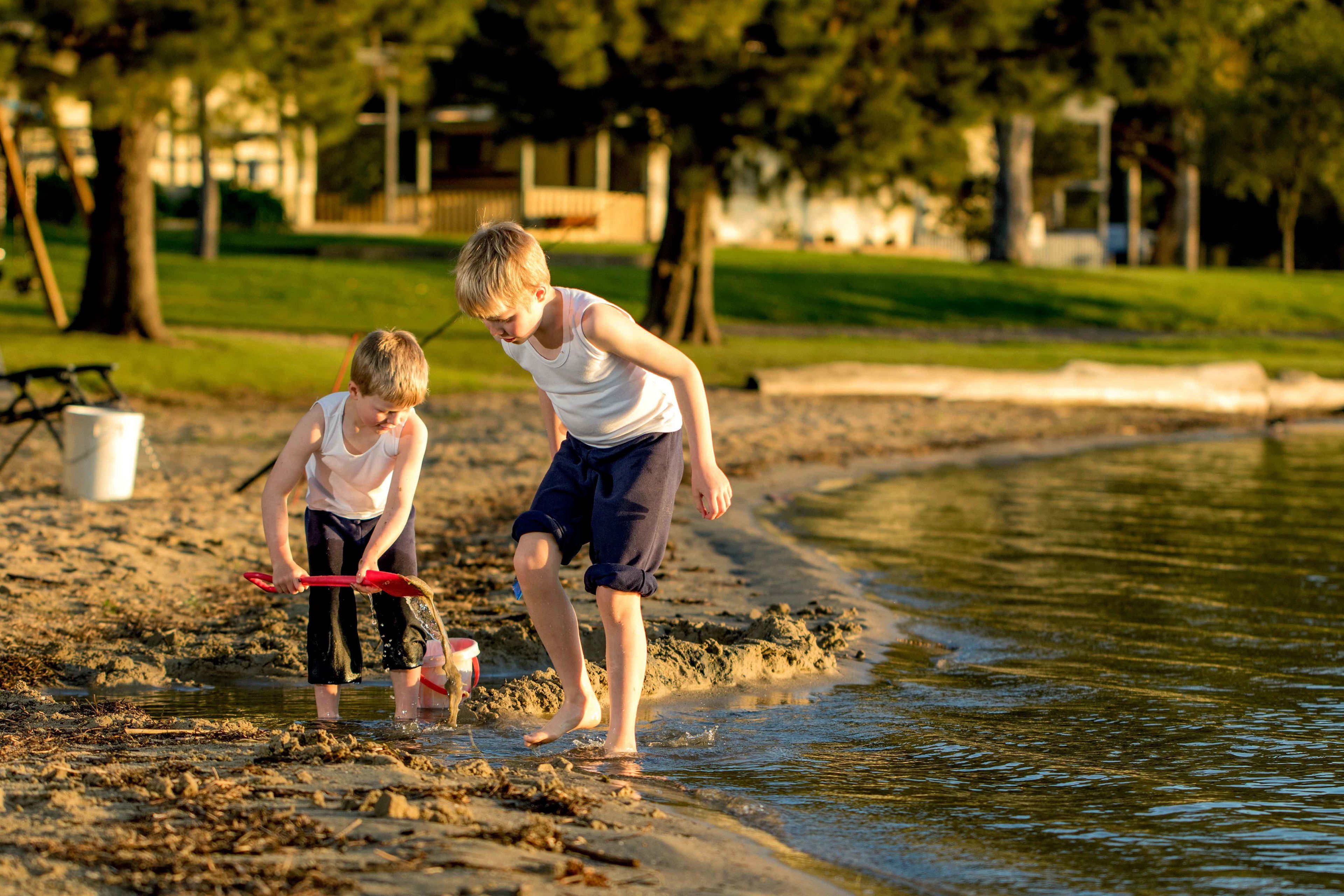 Two children playing in shallow water near a sandy shore.