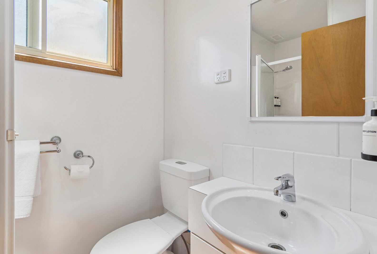 A bathroom with a toilet, sink, and mirror.