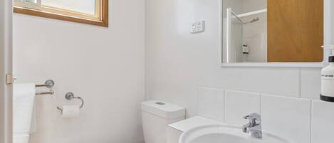 A bathroom with a toilet, sink, and mirror.