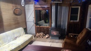 A cozy living room with a sofa, a wooden table, a fireplace, and a window. - Pupu Rangi Nature Sanctuary - Conservation Area (Donnellys Crossing)